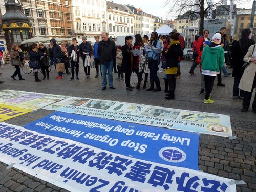 Para pejalan kaki membaca poster Falun Gong di pusat kota Kopenhagen selama akhir pekan-tentang penganiayaan / penyiksaan