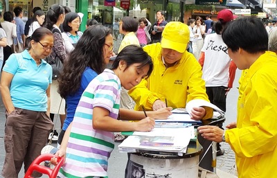 Salvia (kiri) dan putrinya Rayna dan Canbice dari Filipina menandatangani petisi untuk mendukung Falun Gong.