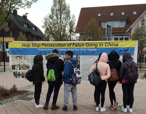Para turis membaca informasi tentang Falun Gong dan penganiayaan