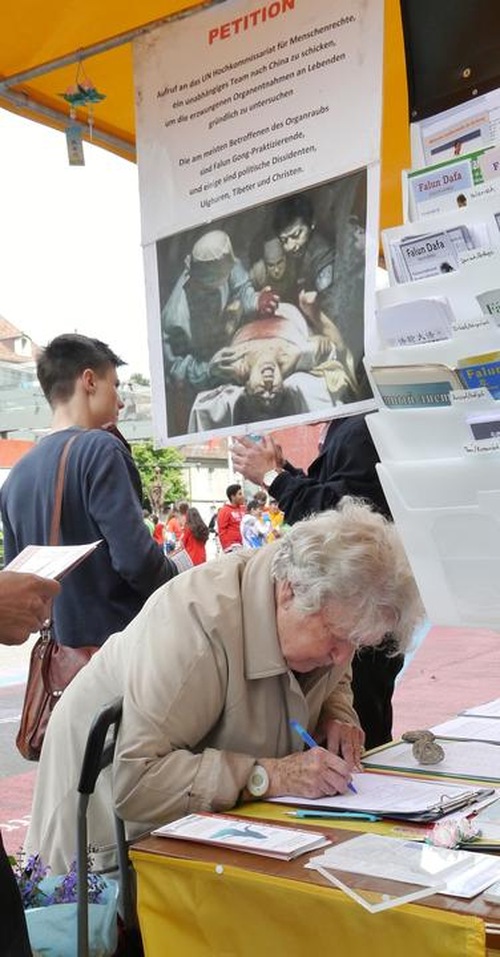 Orang yang lewat di stasiun kereta api di Bern menandatangani petisi yang mengecam penganiayaan terhadap Falun Gong.