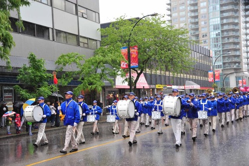 Tian Guo Marching Band memimpin praktisi Falun Dafa di tengah hujan lebat selama Parade Tahunan Hyack International ke 45 di New Westminster.