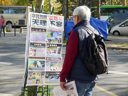 Turis-turis membaca poster-poster tentang Falun Gong dan penganiayaan di Menara Eiffel