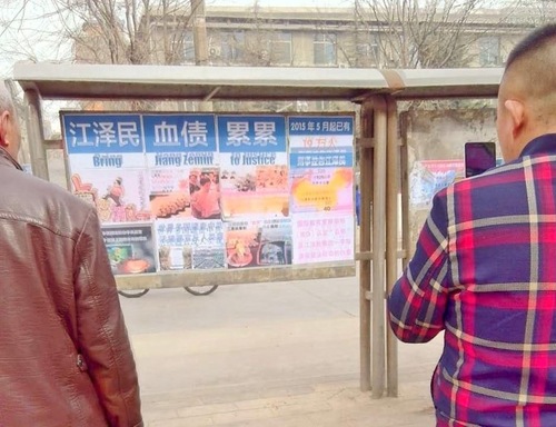 Dua orang yang lewat membaca poster di sebuah kota kecil di Provinsi Shanxi. poster ini berjudul 