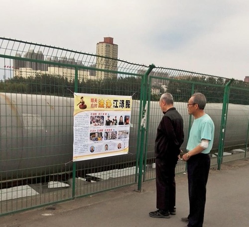 Orang yang lewat membaca poster tuntutan hukum terhadap mantan pemimpin Tiongkok Jiang Zemin di Kota Taiyuan, Provinsi Shanxi. Lebih dari 200.000 tuntutan hukum telah diajukan sejak bulan Mei lalu karena Jiang Zemin menganiaya Falun Gong.