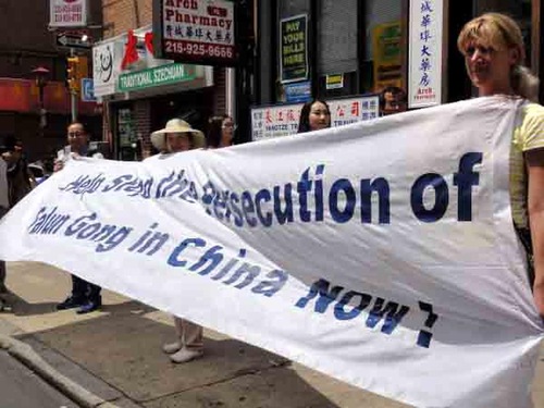 Irine Foxson (kanan) memegang spanduk Falun Gong di bawah sinar matahari selama tiga jam.