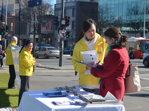 Para pejalan kaki menonton kegiatan dan menandatangani petisi yang mendukung penuntutan terhadap mantan pemimpin Tiongkok Jiang Zemin