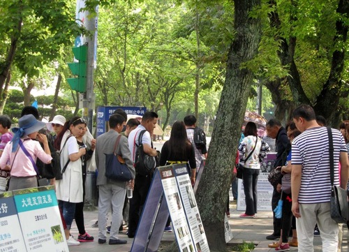 Papan informasi dipajang oleh praktisi Falun Gong di depan Memorial Hall
