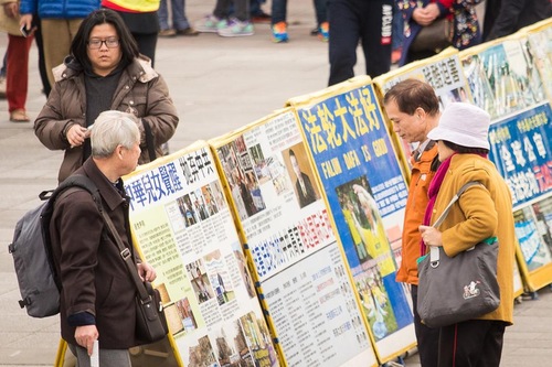 Para wisatawan mempelajari tentang Falun Gong dan penganiayaan di Tiongkok