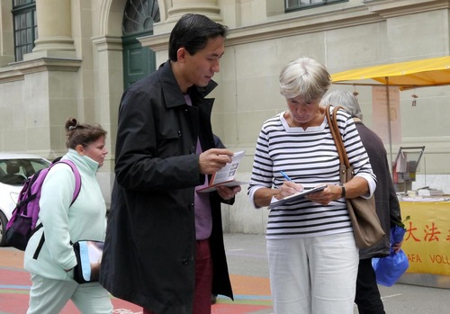 Orang yang lewat di stasiun kereta api di Bern menandatangani petisi yang mengecam penganiayaan terhadap Falun Gong.