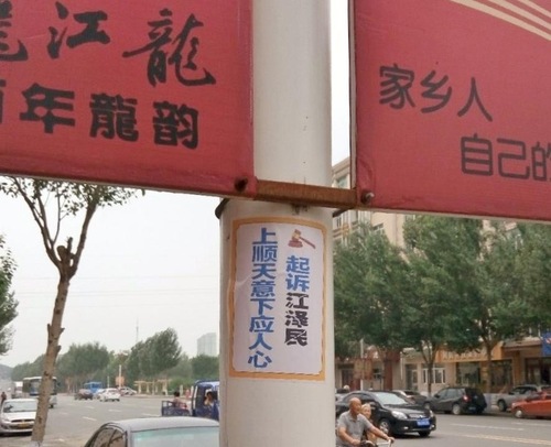 Poster di bawah billboard: “Mengikuti Kehendak Langit untuk Mengadili Jiang Zemin”