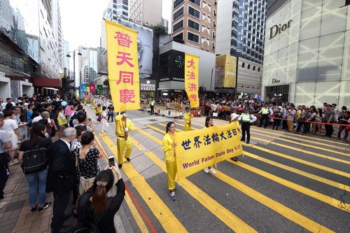 Wisatawan dan penduduk Hong Kong mengambil video dan gambar pawai akbar praktisi Falun Gong.