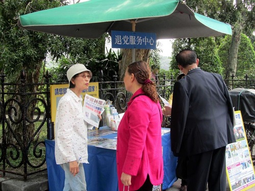 Seorang praktisi Falun Gong (putih) berbicara dengan seorang Wisatawan Tiongkok tentang mundur dari Partai Komunis Tiongkok.