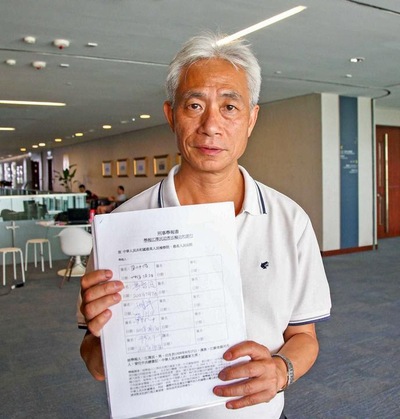 Leung Yiu-chung memegang sebuah formulir laporan kriminal terhadap Jiang Zemin yang telah ditandatangani