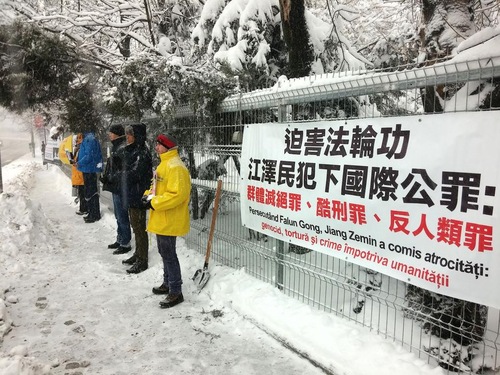 Praktisi dengan penuh damai memprotes di depan Kedutaan Besar Tiongkok sambil memegang foto praktisi Falun Gong yang telah meninggal akibat penganiayaan rezim komunis Tiongkok.