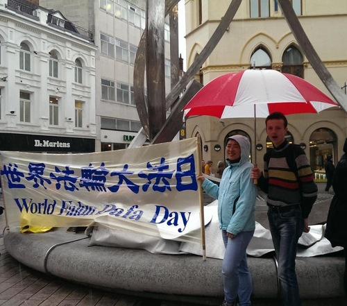 Orang-orang menandatangani petisi dalam hujan untuk mendukung perlawanan damai Falun Gong.