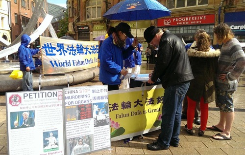 Orang-orang menandatangani petisi dalam hujan untuk mendukung perlawanan damai Falun Gong.