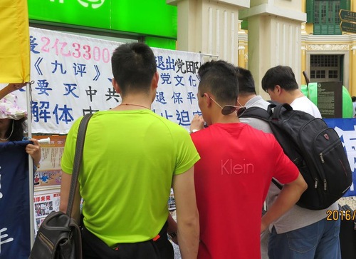 Turis Tiongkok membaca informasi Falun Gong.