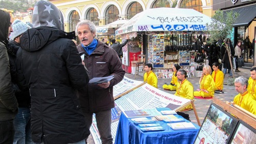Pejalan kaki di Stasiun Kereta Athena mendengar praktisi menjelaskan Falun Dafa.