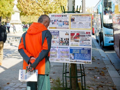 Turis Tiongkok sedang membaca poster tentang penganiayaan brutal terhadap Falun Gong di Tongkok
