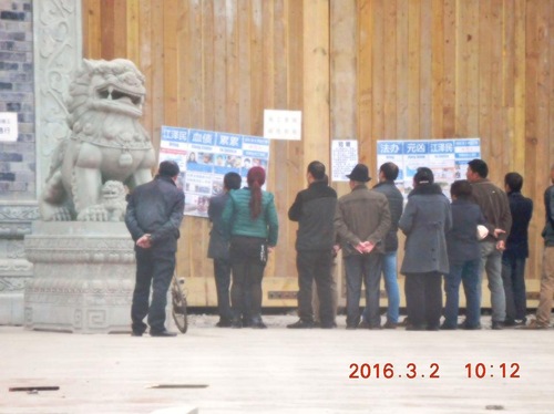 Orang-orang membaca tentang penganiayaan Falun Gong di sebuah jalan di Nanchong, Provinsi Sichuan.