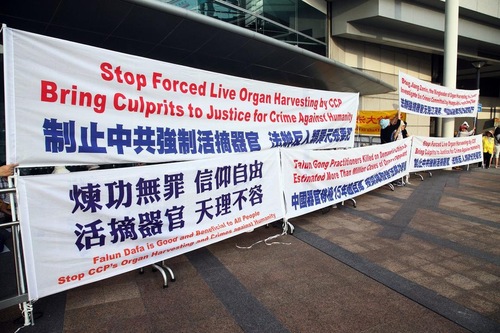 Spanduk dipajang praktisi Falun Gong di luar Kongres Internasional Organisasi Transplantasi ke 26.
