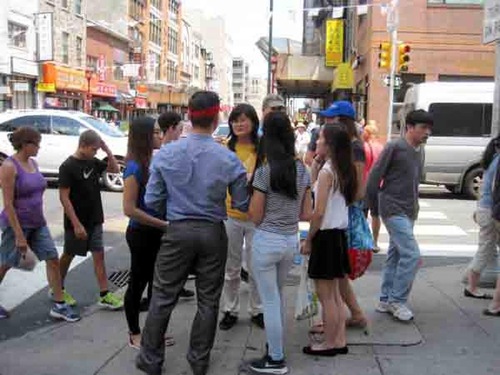 Seorang praktisi Falun Gong (tengah, berbaju kuning) memberi tahu masyarakat tentang penganiayaan.