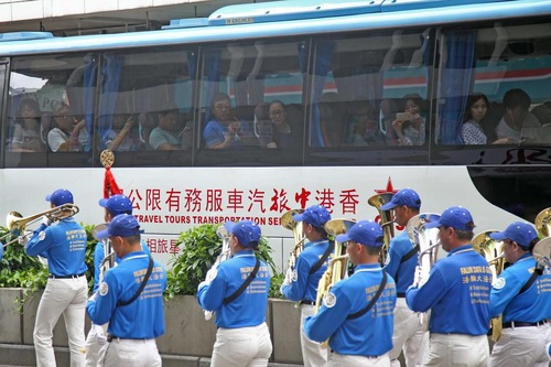 Wisatawan Tiongkok di bus tur mengambil gambar saat Tian Guo Marching Band lewat. 