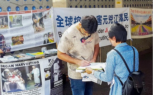 Para pendukung menandatangani petisi Falun Gong untuk menuntut Jiang Zemin