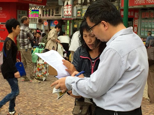 Orang-orang menandatangani petisi mendukung perlawanan damai Falun Gong.