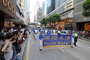 法轮功反迫害游行队伍由天国乐团领头，步入广东道，马路两旁站满了观看和拍照的市民及游客。
