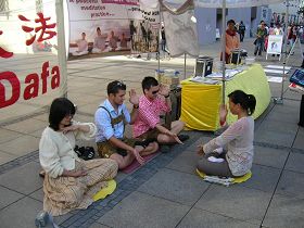 '身穿巴伐利亚传统服装的两位小伙子，正跟着法轮功学员炼习功法。'