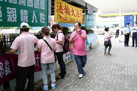 “香港青年关爱协会”负责人之一林国安（穿粉红横条文者）在现场指挥冲击法轮功真相点，他与中国井冈山市一名特聘政协委员“同名同姓”，有消息称此人就是周永康阵营专程从中国派来香港负责冲击法轮功真相点的中共特工。